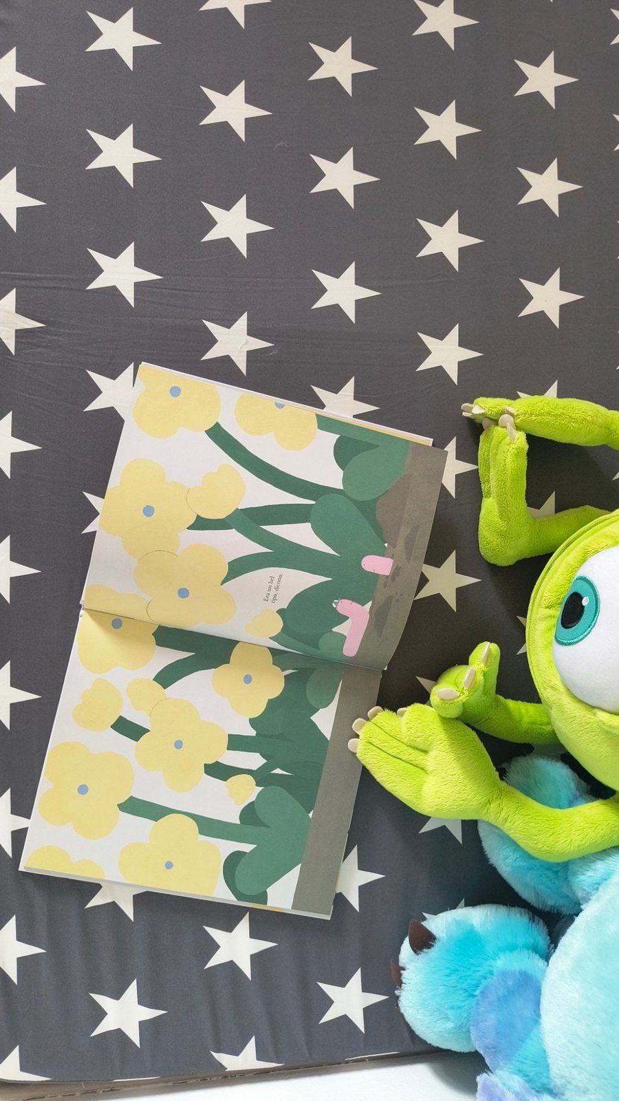 Un albo illustrato aperto e un peluche appoggiati su un cuscino a stelle